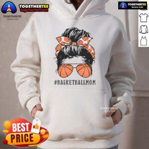 Pretty basketball mom with a messy bun, wearing sunshades and a hoodie, proudly supporting her child on the court.