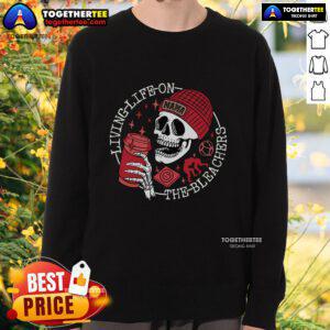 Mama Skull sweatshirt on a woman enjoying life on the bleachers, showcasing a trendy and casual style.