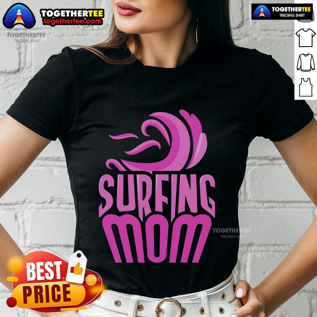 Top surfing mom in a stylish tee, showcasing surfer sayings while holding a surfboard on the beach.