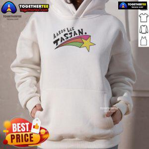 Happy Aaron Lee Tasjan wearing a colorful rainbow star hoodie, showcasing vibrant style and joyful expression.