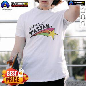 Alt Text: Happy Aaron Lee Tasjan wearing a colorful rainbow star t-shirt, showcasing vibrant design and joyful expression.