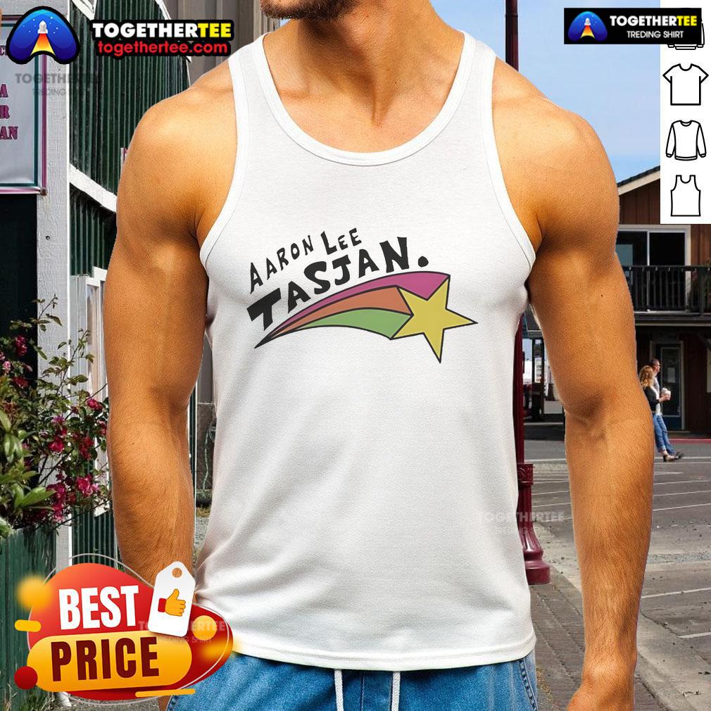 Happy Aaron Lee Tasjan wearing a colorful rainbow star tank top, radiating joy and style at a vibrant outdoor event.