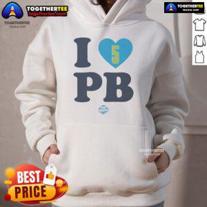Alt Text: Happy Paige Bueckers wearing a stylish I Love PB Dallas Wings hoodie, showcasing her love for basketball and team spirit.