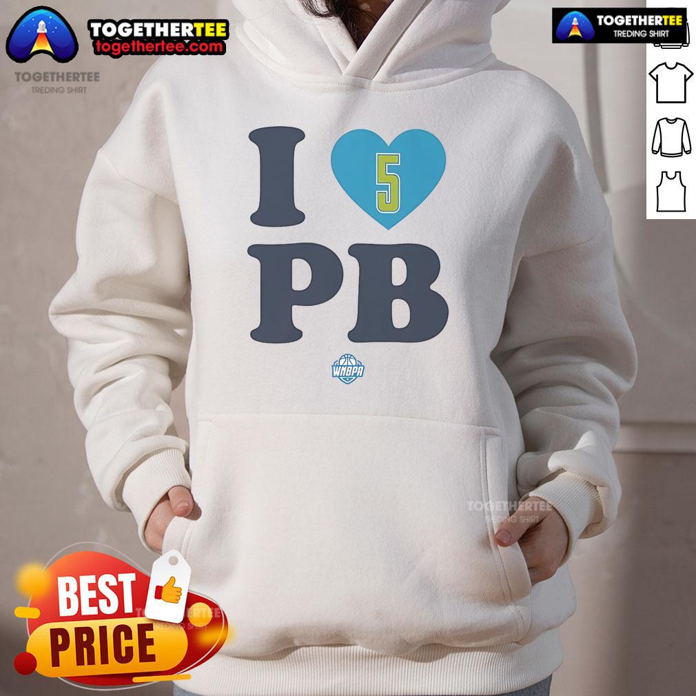 Alt Text: Happy Paige Bueckers wearing a stylish I Love PB Dallas Wings hoodie, showcasing her love for basketball and team spirit.