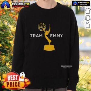 Tramell Tillman wearing an Emmy sweatshirt while posing next to a tram, showcasing his stylish look and personality.