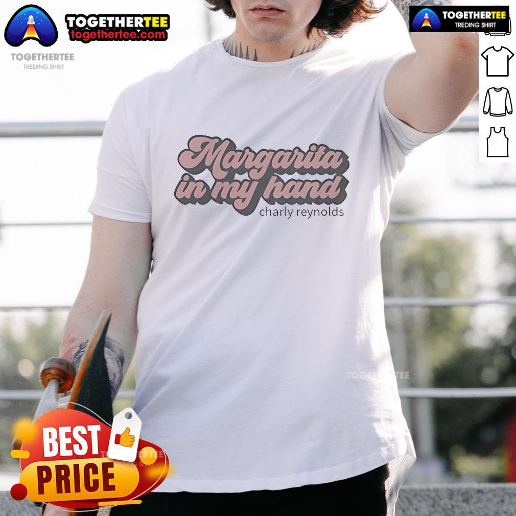 Premium Charly Reynolds Margarita T-shirt featuring a vibrant graphic, held in hand against a sunny outdoor backdrop.