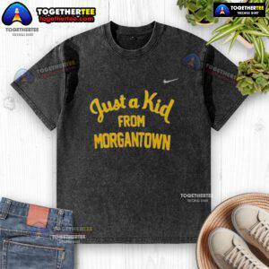 Alt Text: Official West Virginia Mountaineers 'Just A Kid From Morgantown' washed t-shirt displayed on a wooden background.