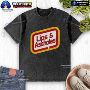 Good Lips and Assholes Washed T-Shirt displayed on a hanger, showcasing its unique graphic design and soft fabric.