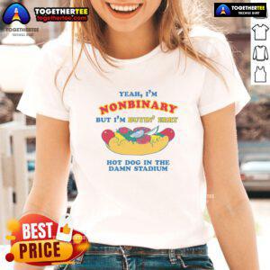 Nonbinary person wearing a 'Nice Yeah I'm Nonbinary' tee, enjoying hot dogs at a stadium event.