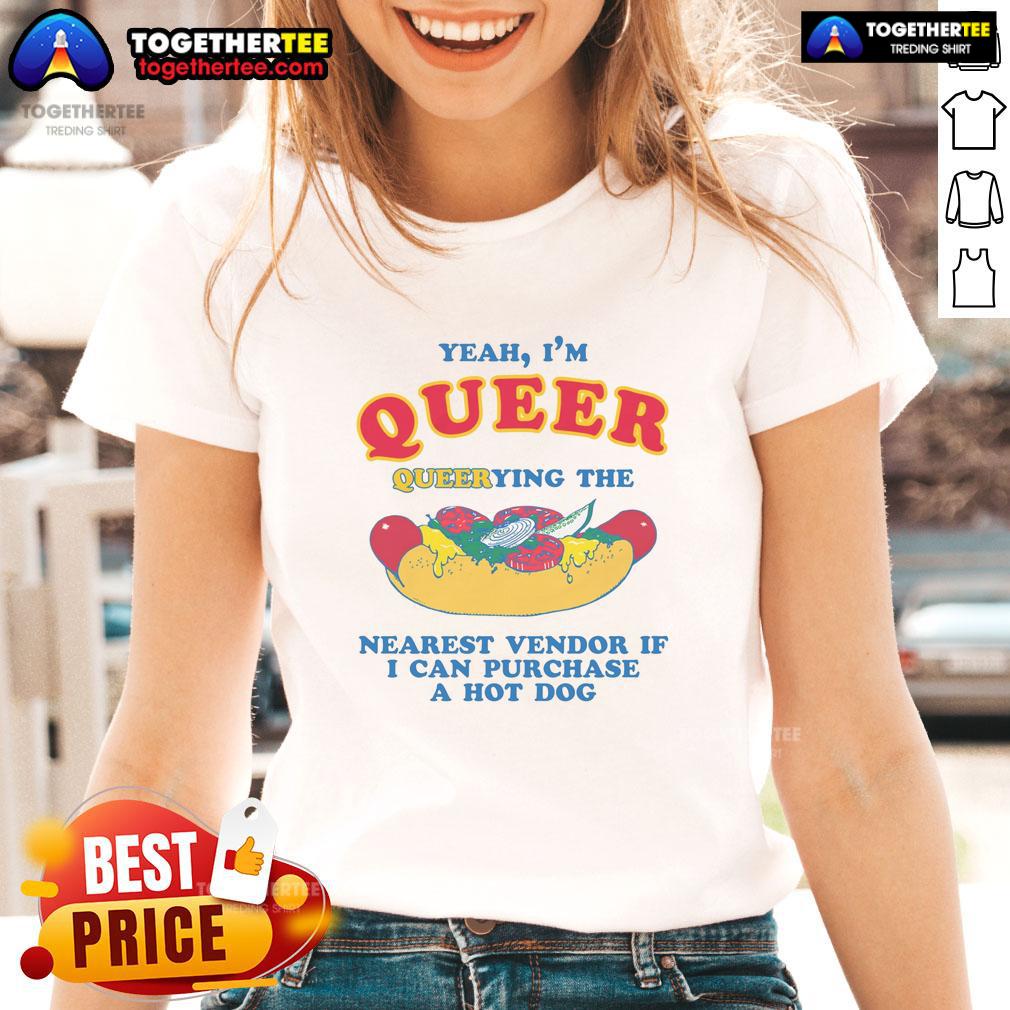 Queer person in a 'Nice Yeah I'm Queer' tee, querying a vendor for a hot dog at a lively street fair.